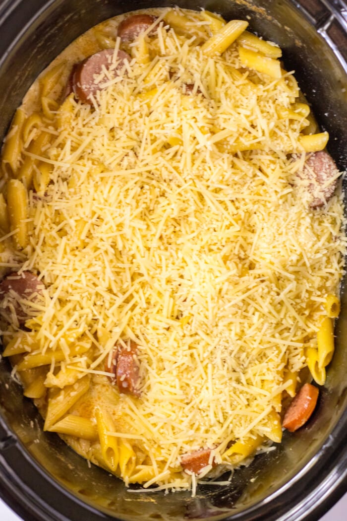 cheese on top of pasta and sausage in slow cooker