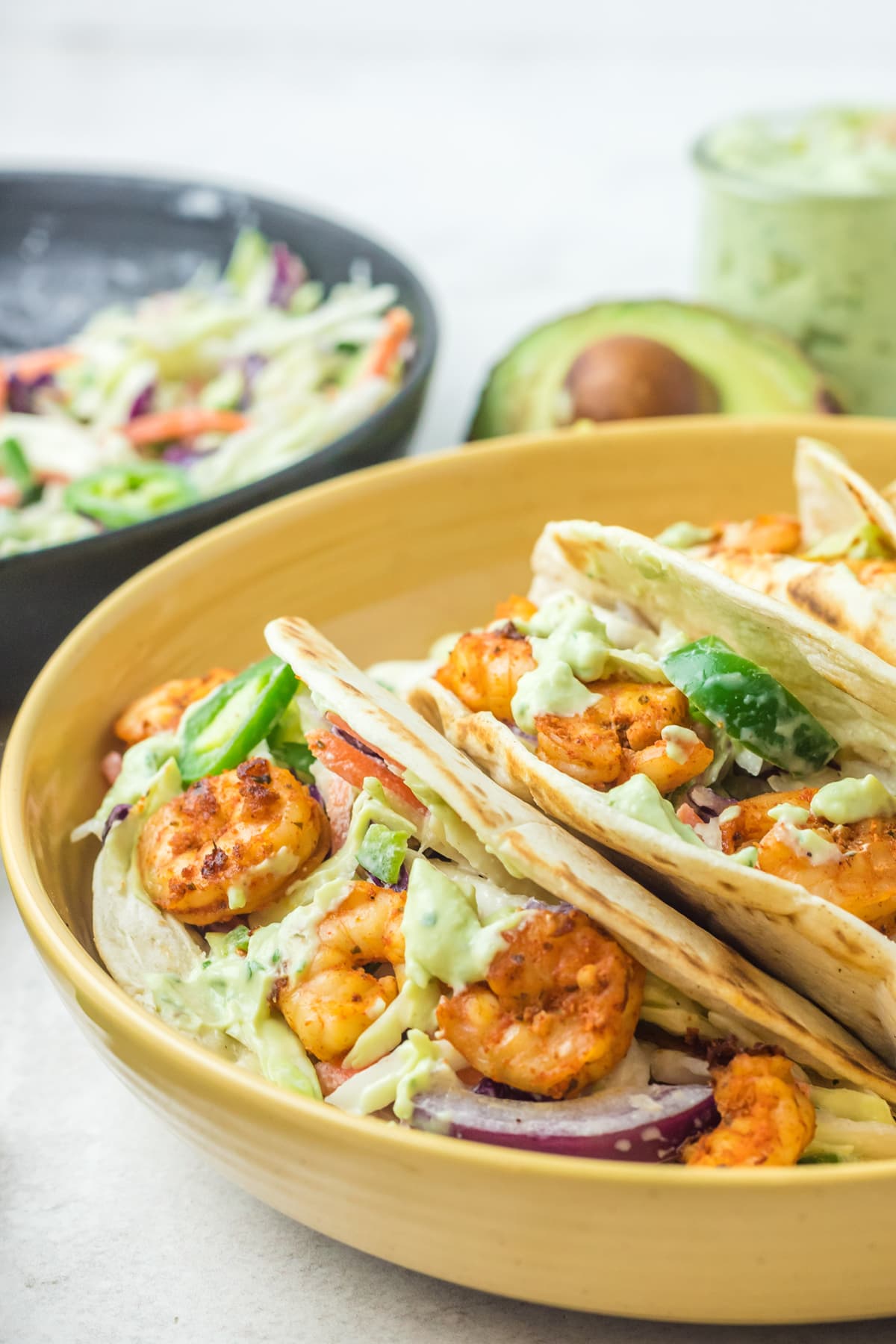 spicy shrimp tacos served in yellow bowl with jalapeno coleslaw