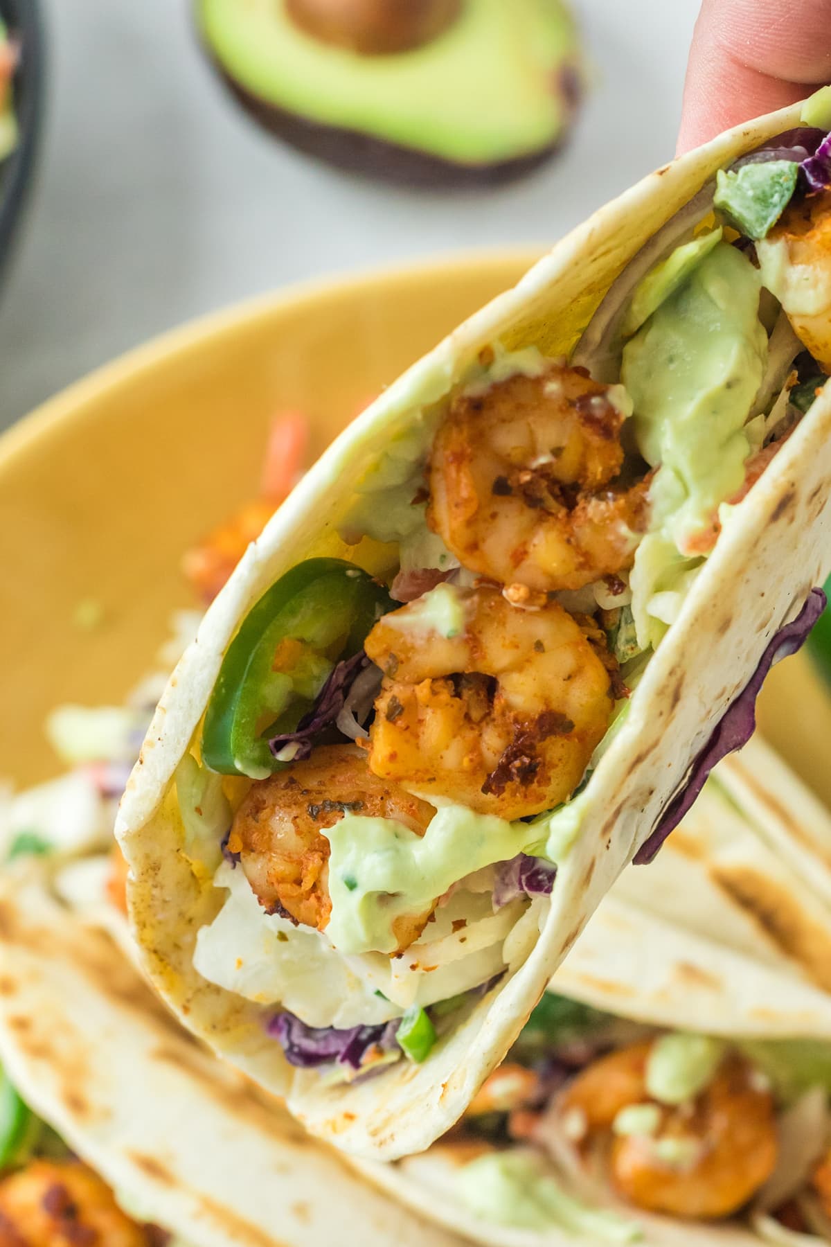 hand holding spicy shrimp tacos