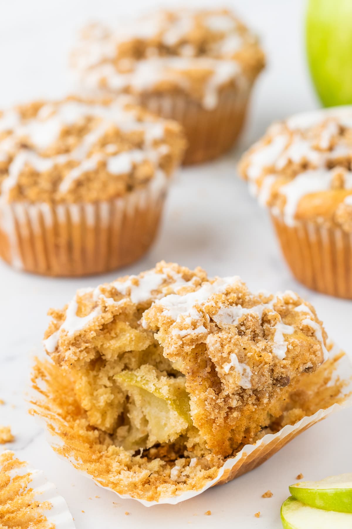 An apple cinnamon muffin with a bite missing to show the apples inside