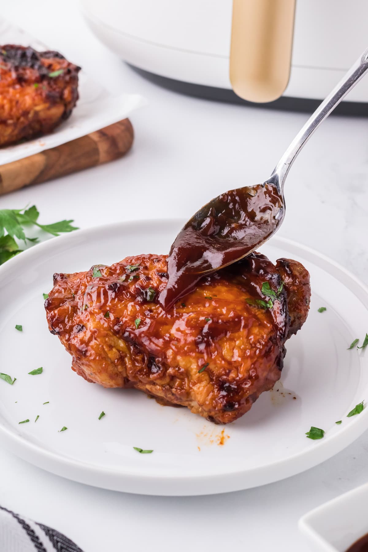 bbq sauce spooned over air fryer chicken thighs