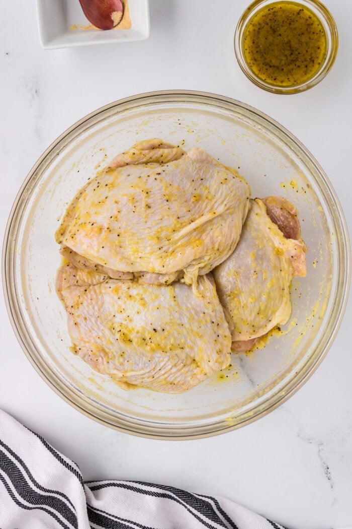 chicken in bowl with oil and seasoning