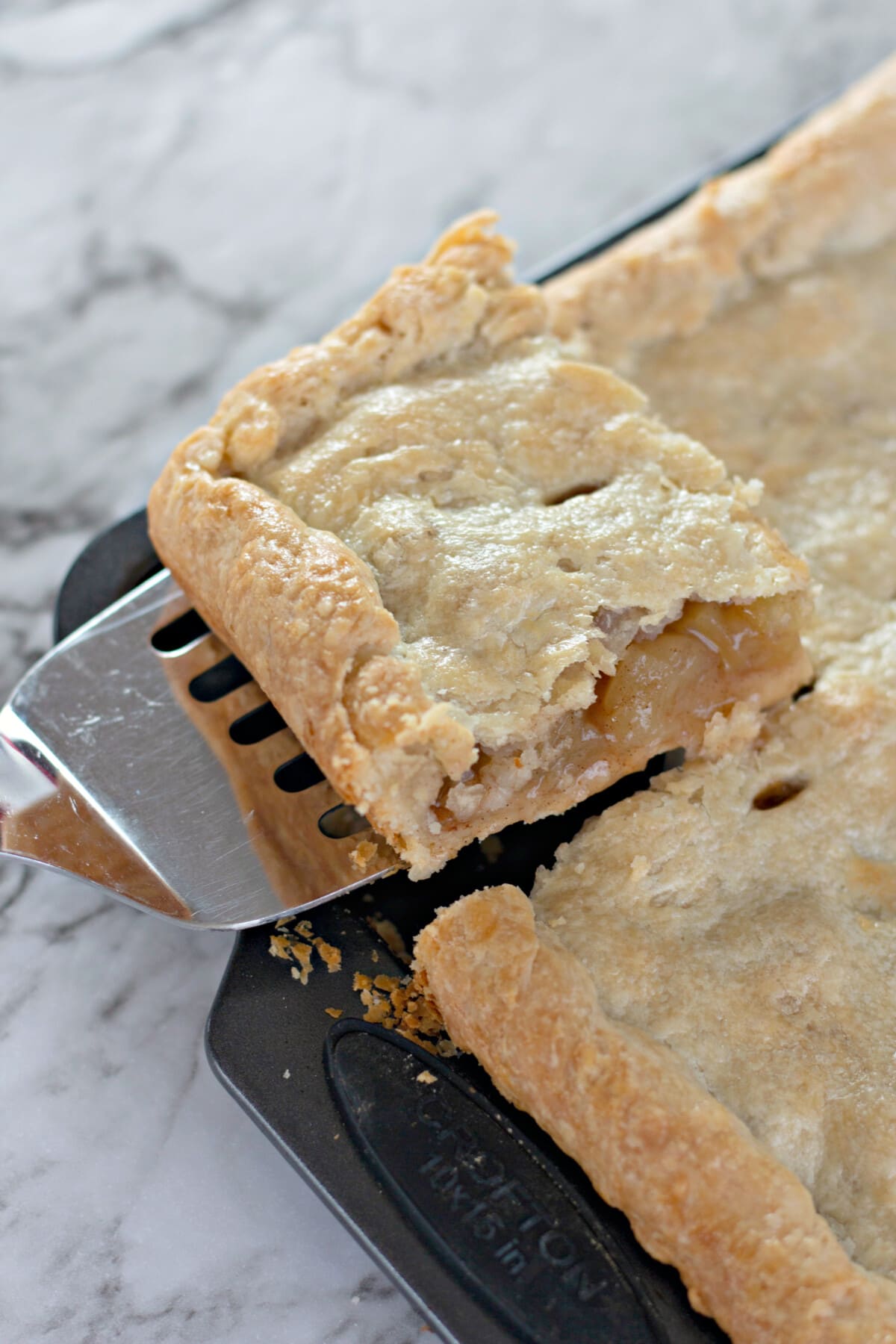 apple slab pie being lifted out with a spatula