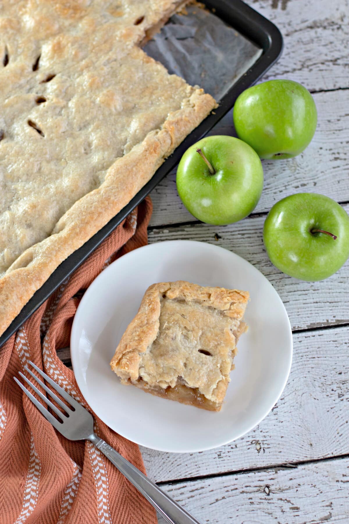 apple slab pie on a white plate with green apples on the side