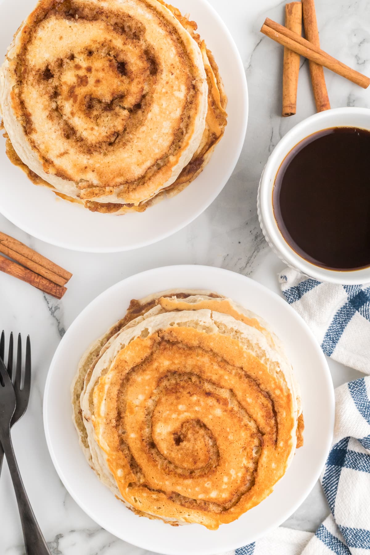 Overhead view of two plates of cinnamon roll pancakes