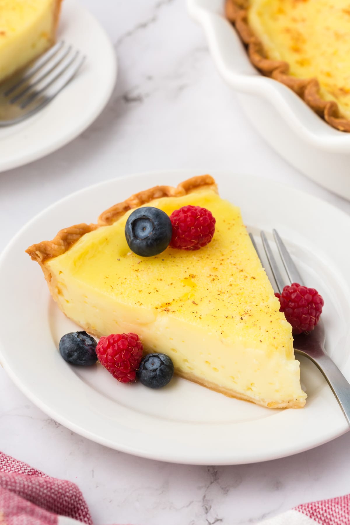 slice of custard pie with berries on white plate