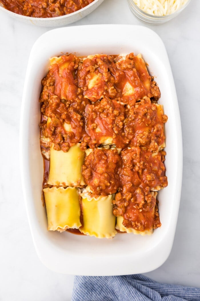 lasagna roll ups in baking dish with sauce on top
