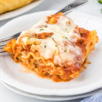 lasagna roll ups on white plate with fork