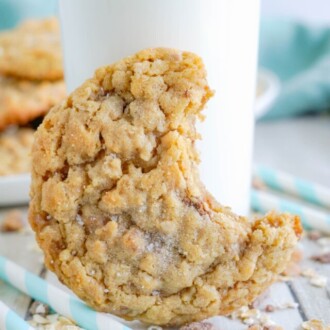 bite out of peanut butter oatmeal cookies with glass of milk