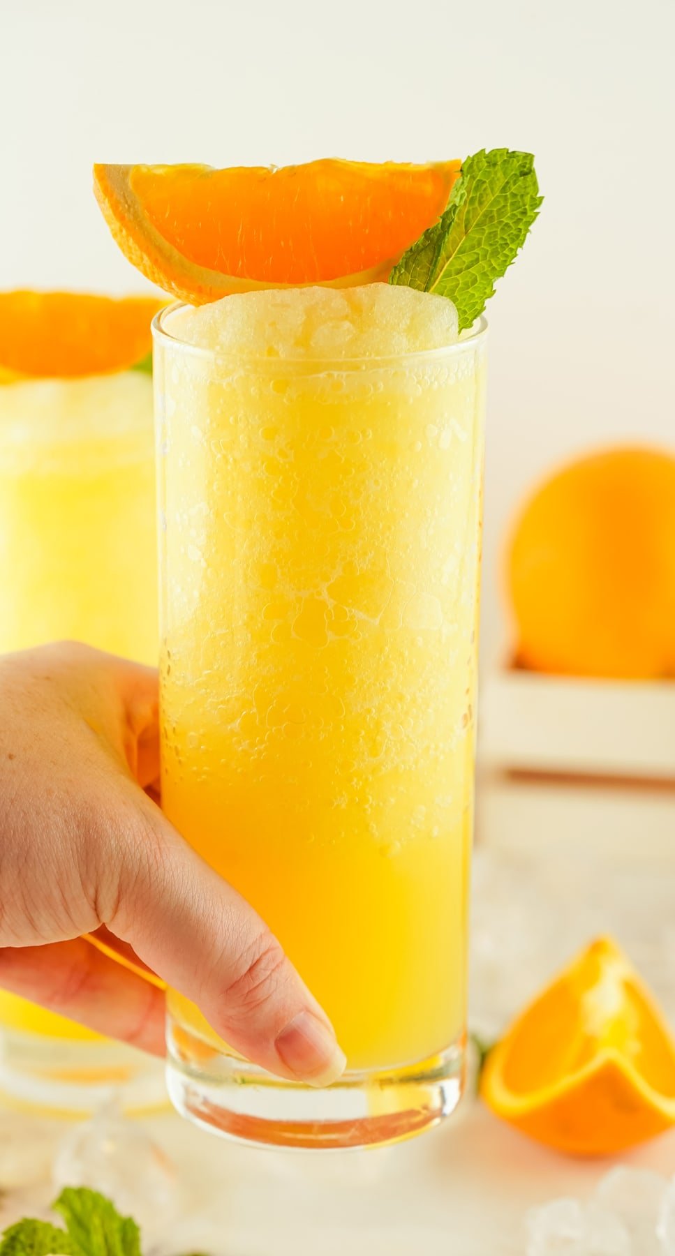 A hand holding a fuzzy navel cocktail