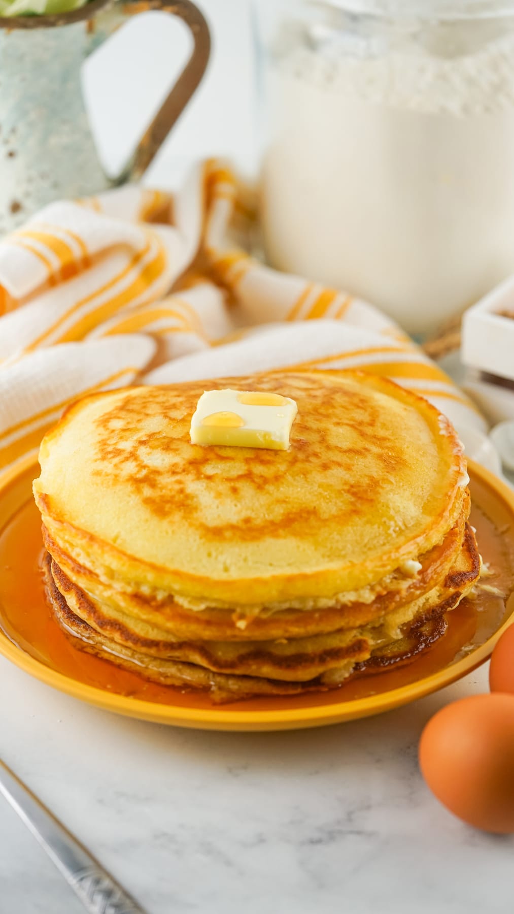 A stack of homemade pancakes topped with butter