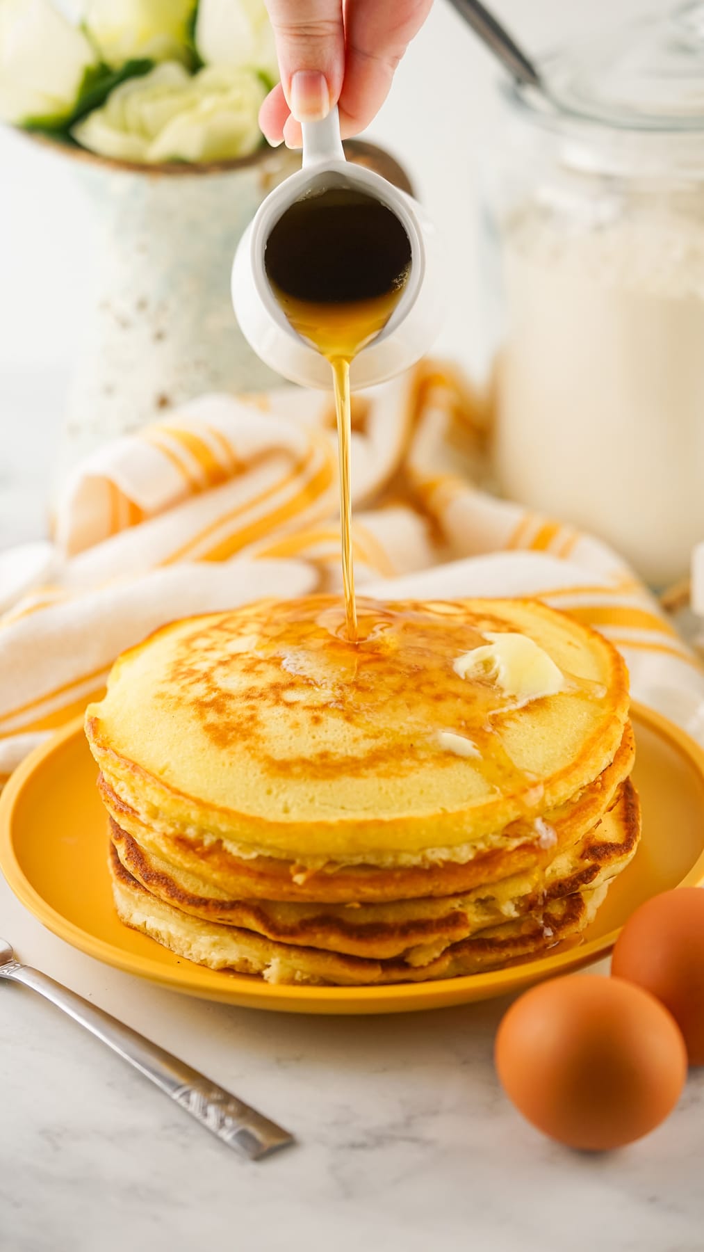 Syrup being drizzled over a stack of pancakes