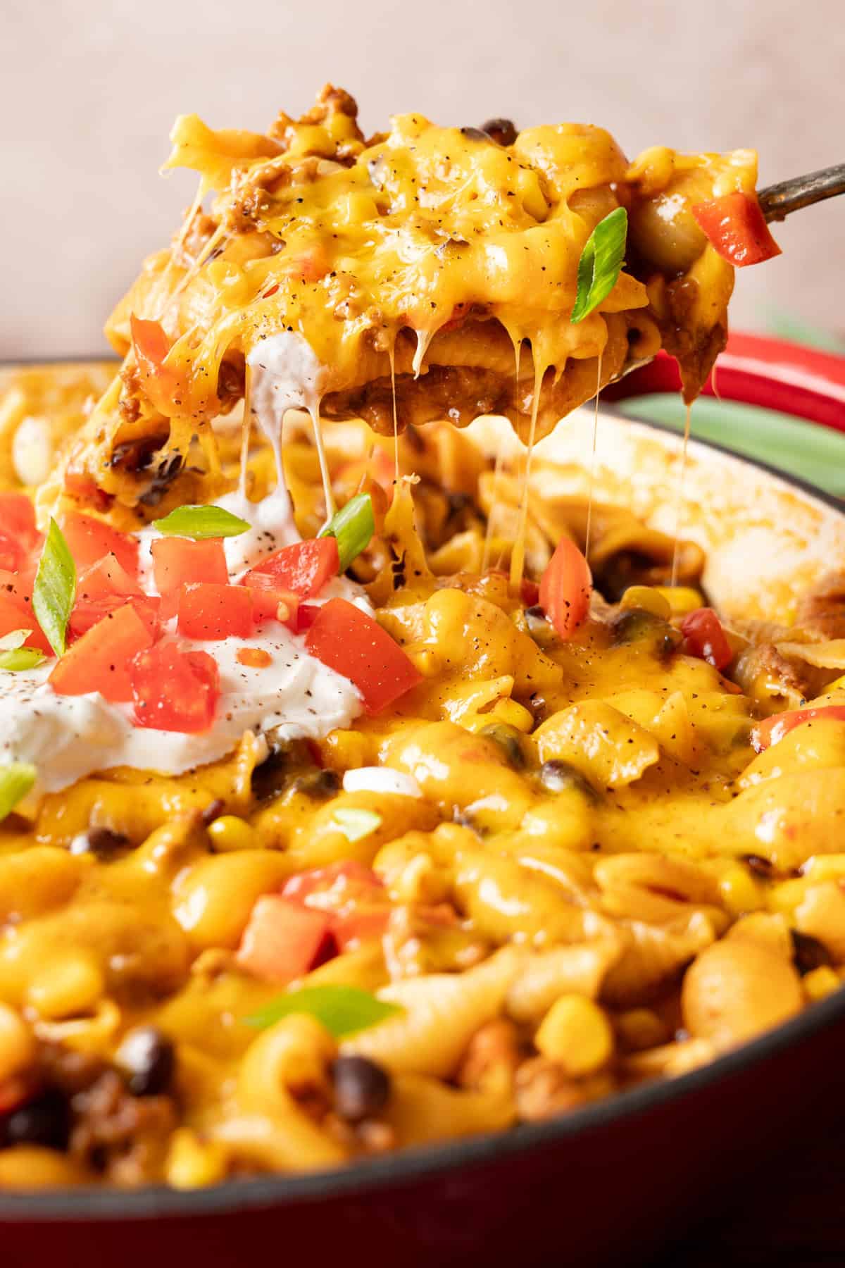 a spoon lifting out a portion of taco pasta from a skillet.