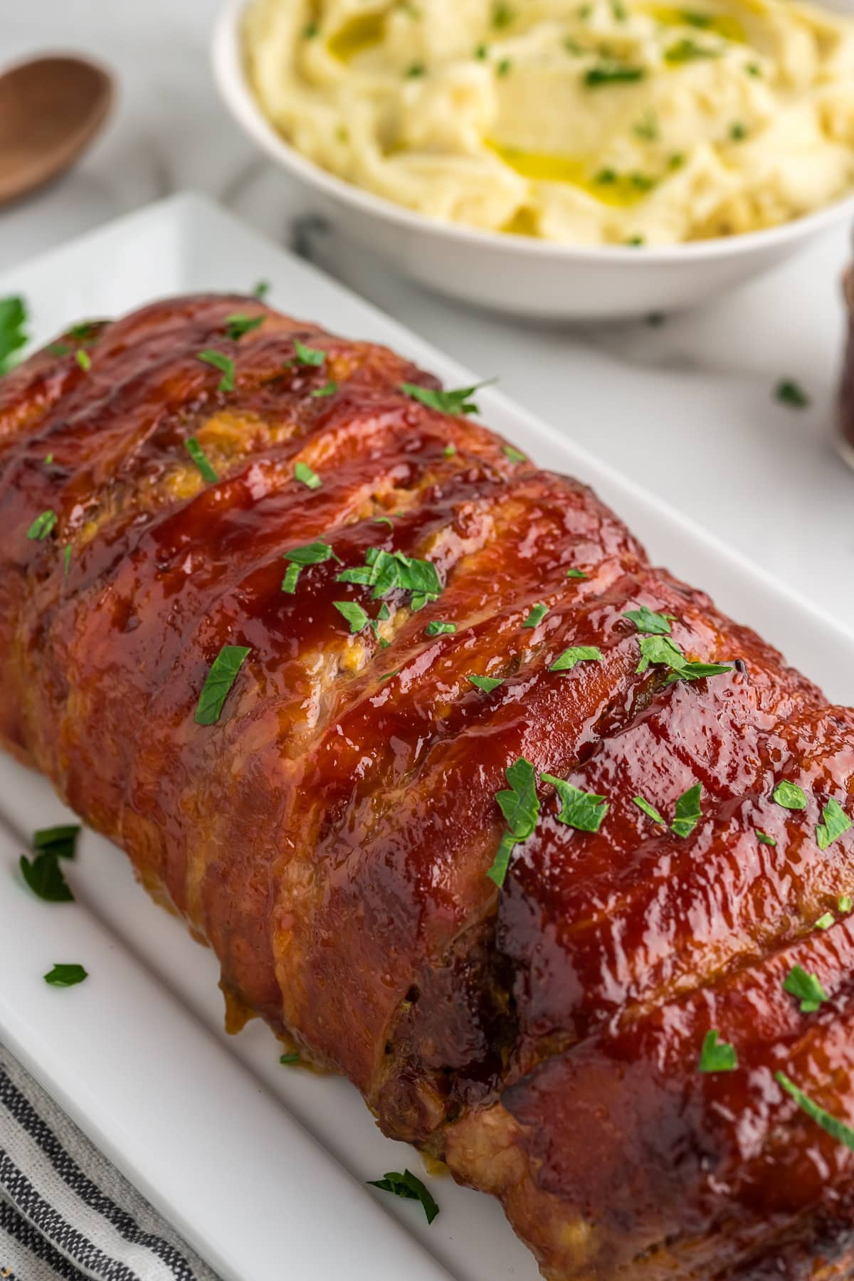 bacon wrapped meatloaf on white serving platter
