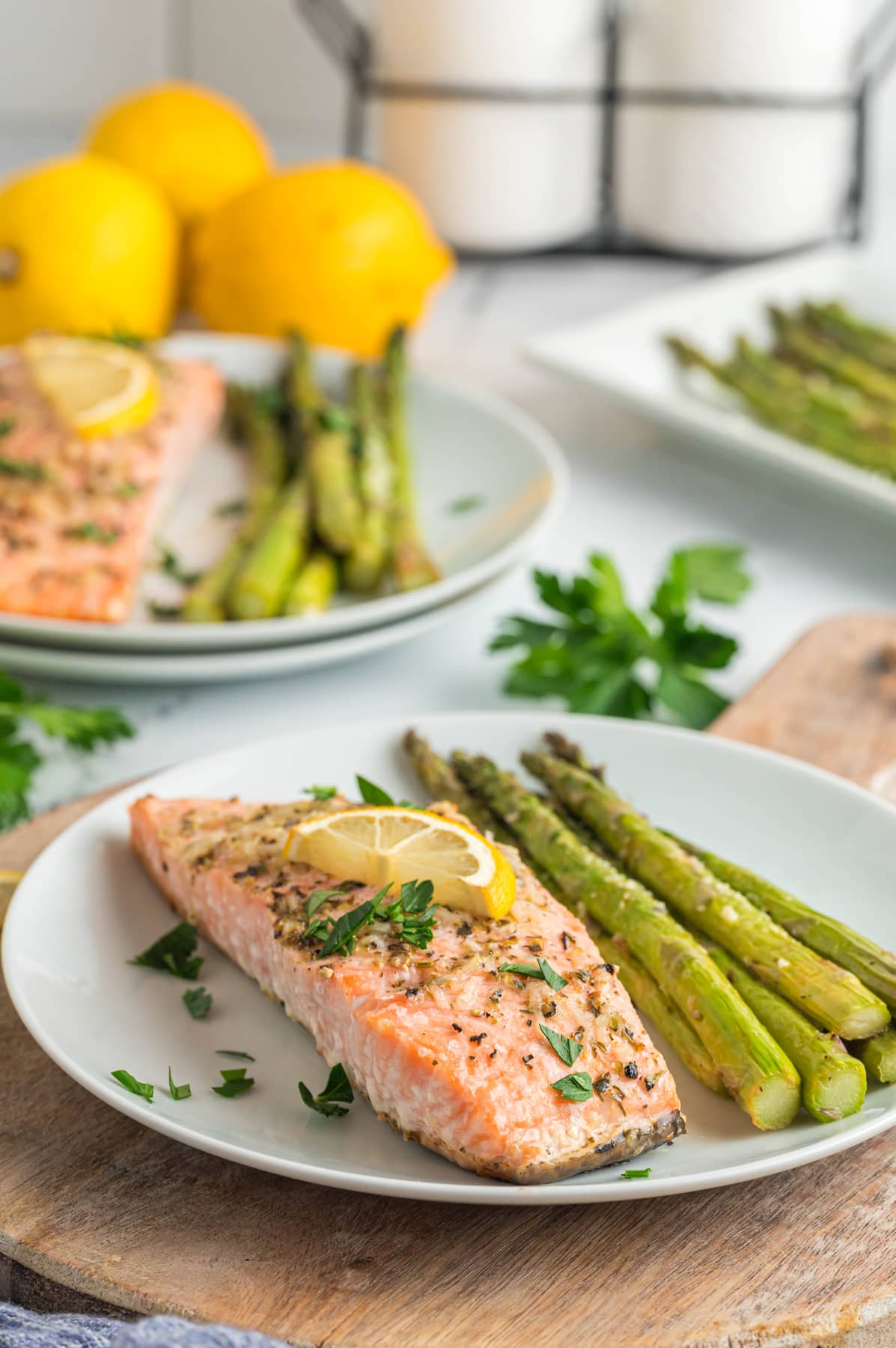 Angled view of two plates of baked salmon with asparagus