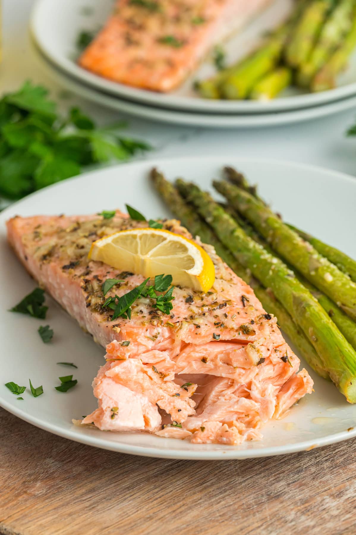 An oven baked salmon filet on a white plate with asparagus