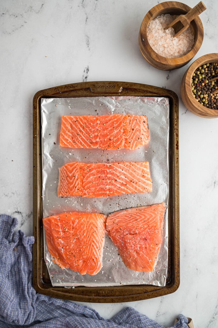 Four salmon filets on a baking sheet