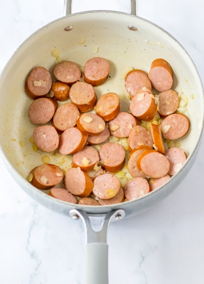 sliced sausage cooked with onion in skillet