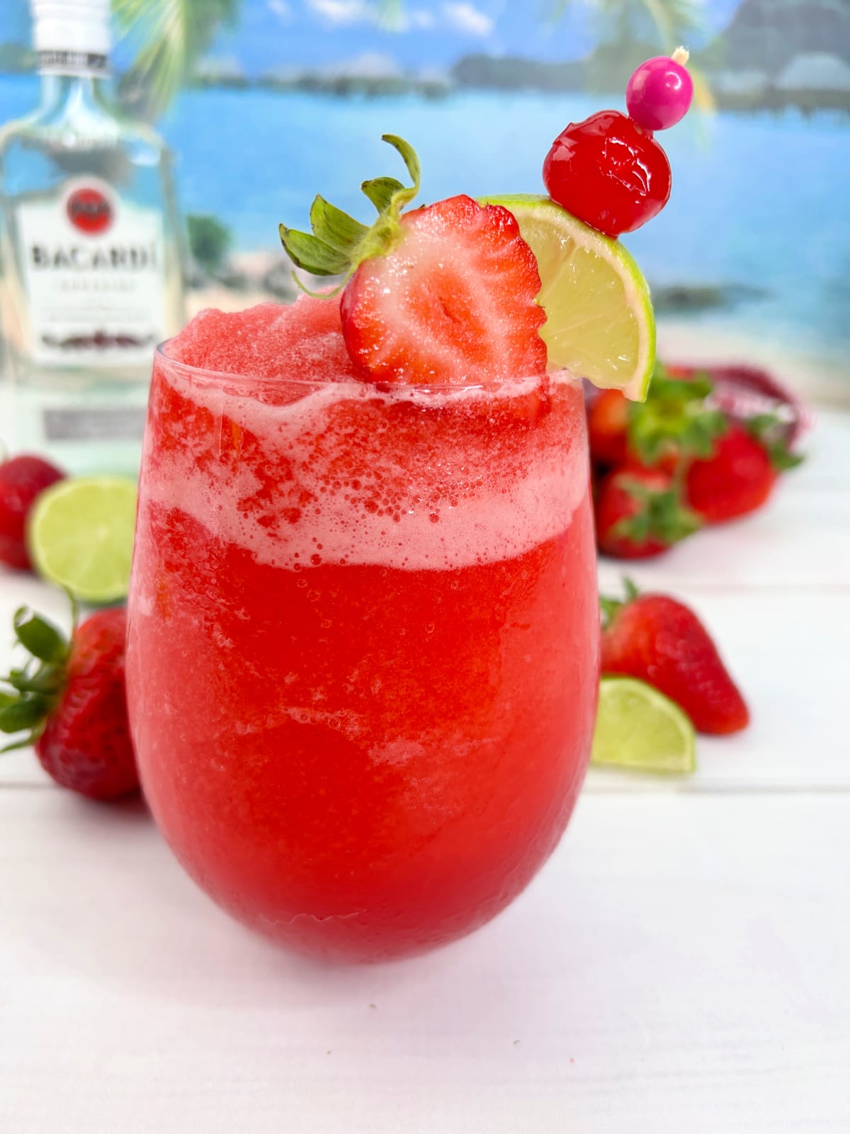 glass with frozen strawberry daiquiri with strawberries and limes