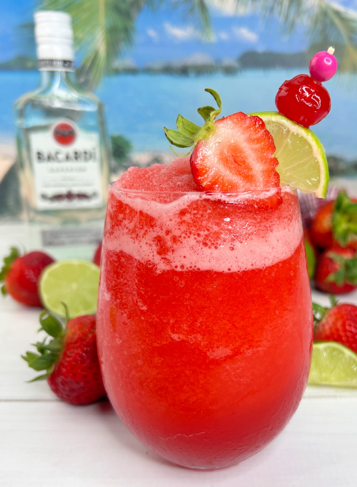 glass with frozen strawberry daiquiri with strawberry, lime and cherry on top