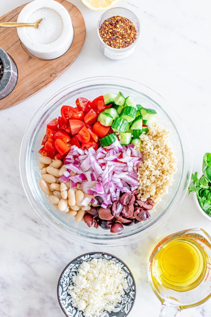 ingredients for mediterranean quinoa salad in glass bowl