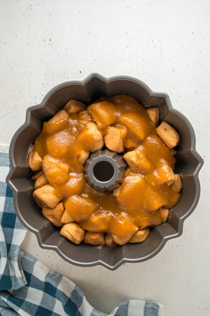Butter and brown sugar poured over pieces of biscuit in a bundt pan