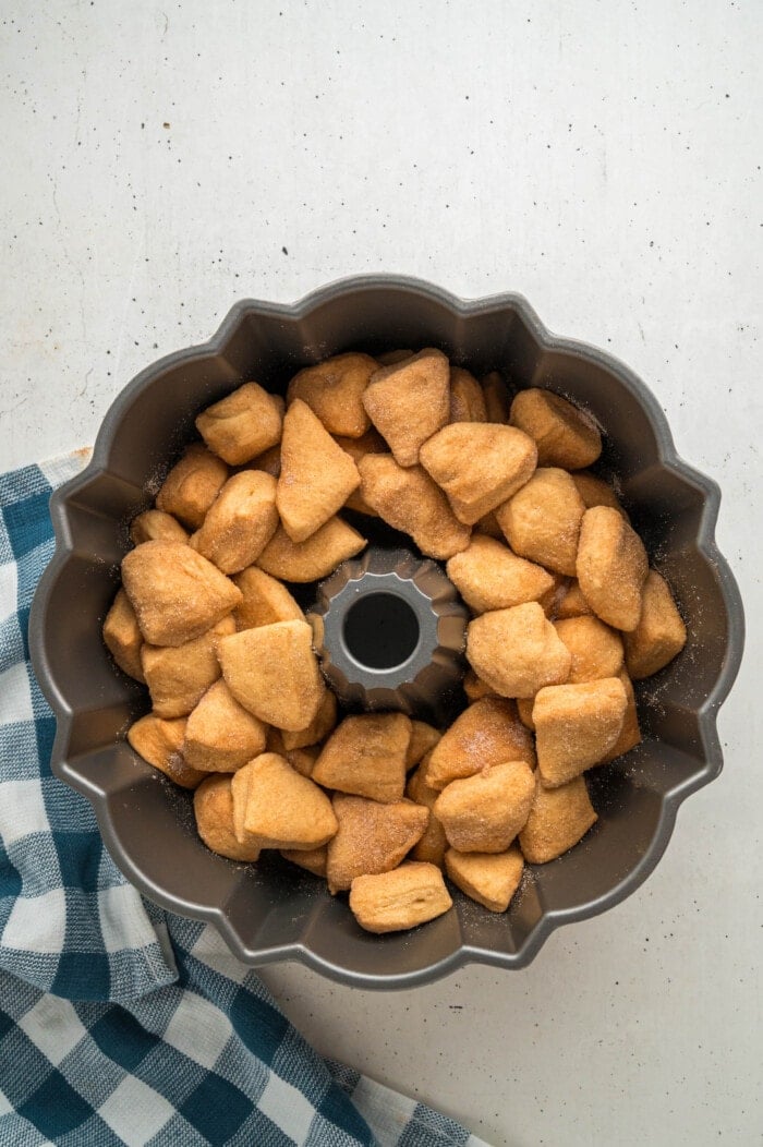 Pieces of biscuit coated with cinnamon sugar in a bundt pan