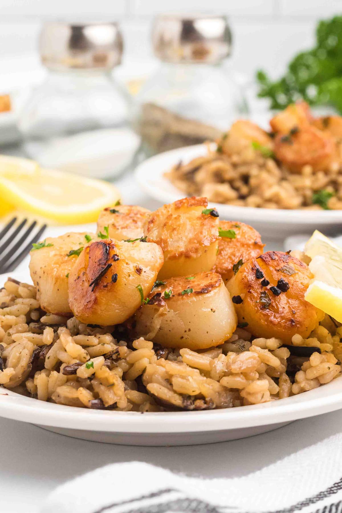 pan seared scallops on plate with brown rice and lemons