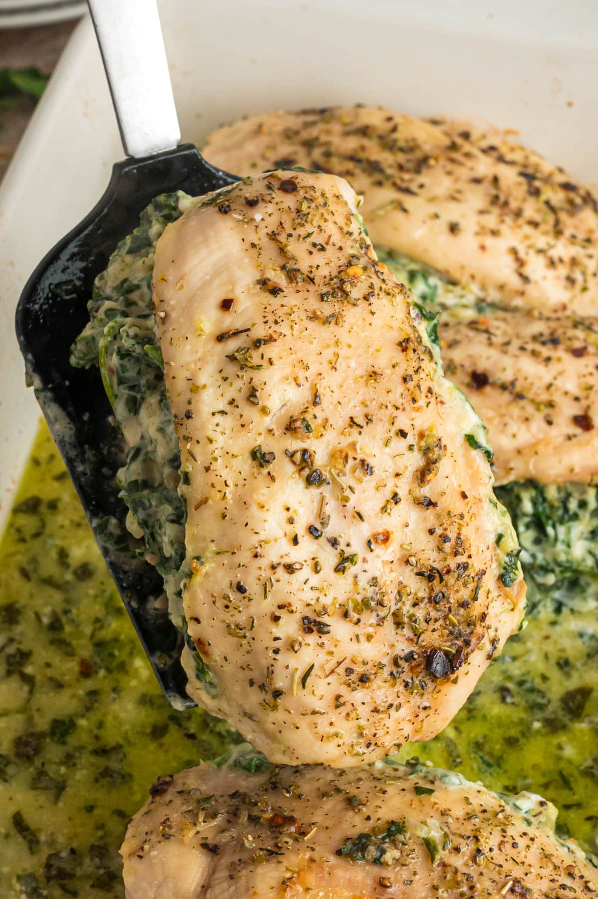 A spatula serving a stuffed chicken breast with spinach