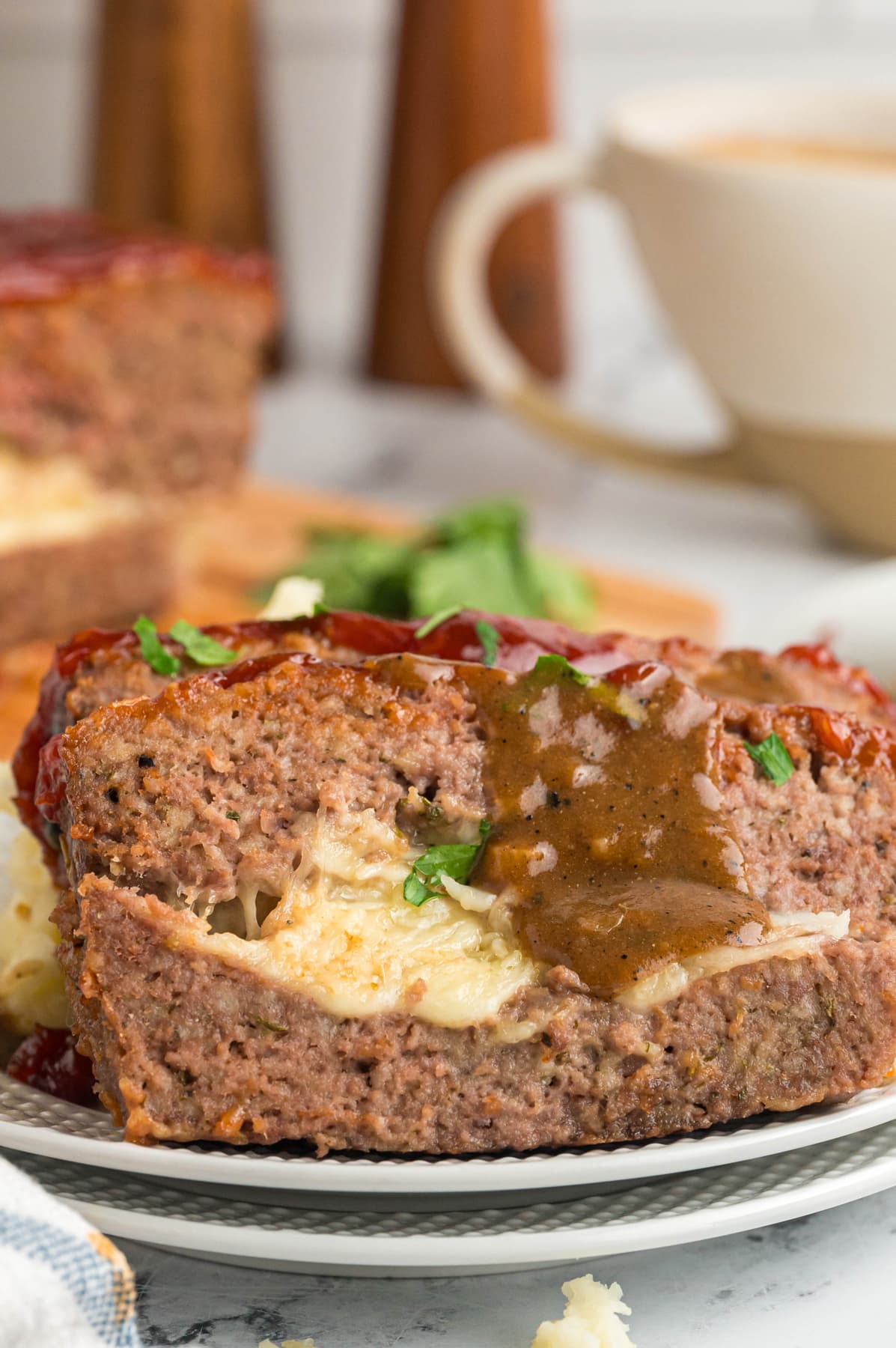 slices of stuffed meatloaf on white plate with gravy