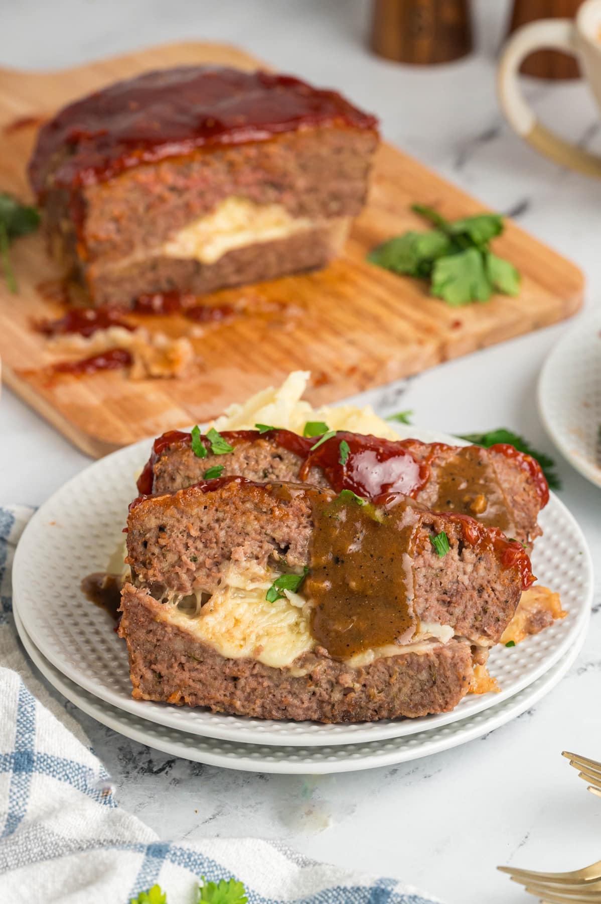 stuffed meatloaf sliced on white plate with gravy