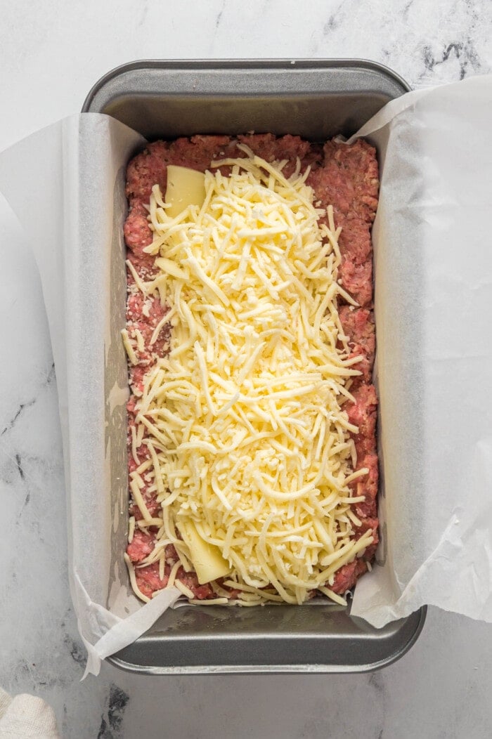 shredded mozzarella cheese on top of cheese slices with meatloaf