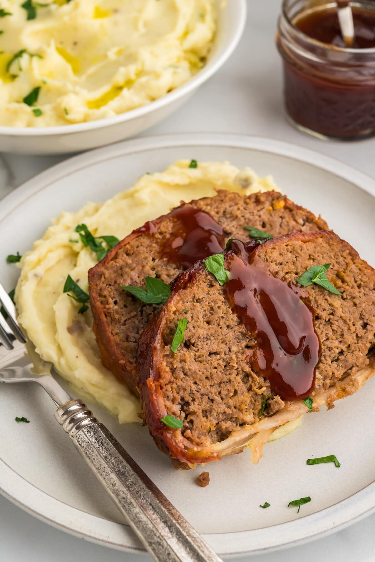 Bacon Wrapped Meatloaf Slices on a plate with mashed potatoes