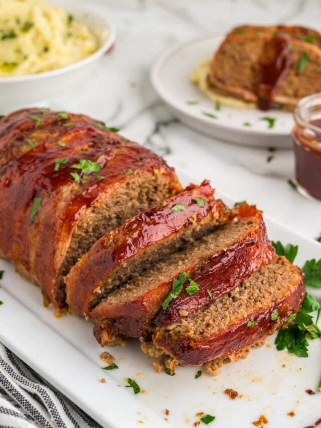 bacon wrapped meatloaf sliced on white serving platter