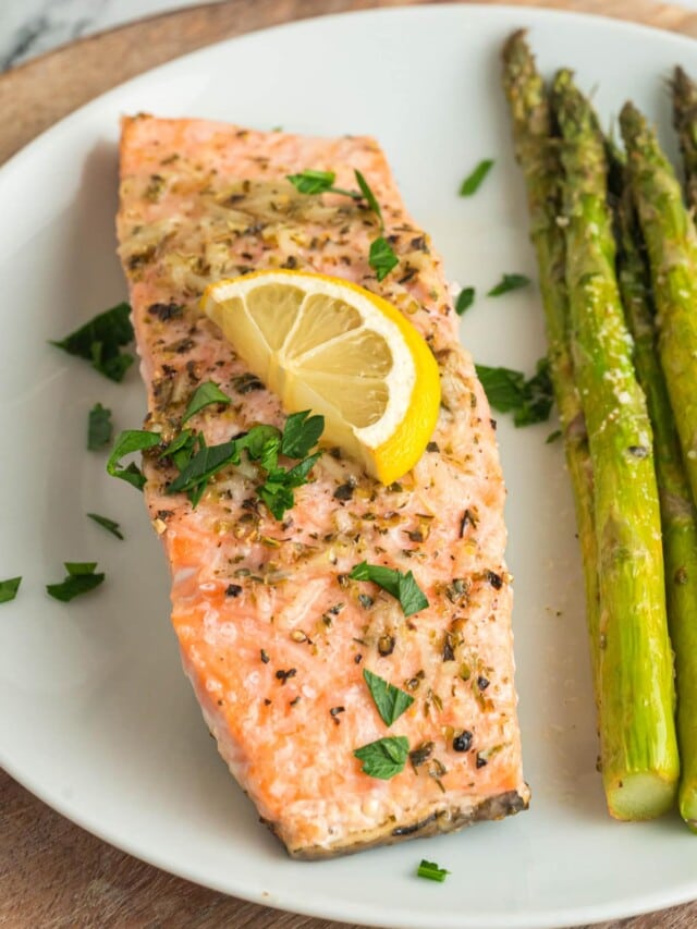 Oven baked salmon on a white plate with asparagus