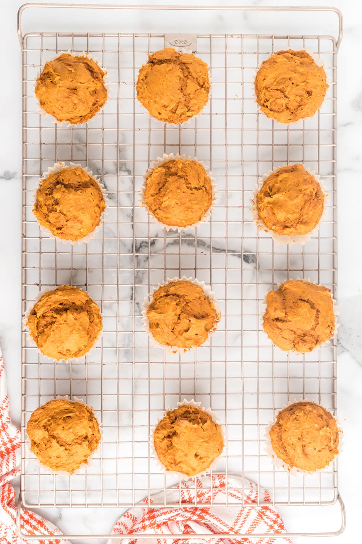 A dozen 2 Ingredient Pumpkin Muffins on a wire cooling rack on a marble background.