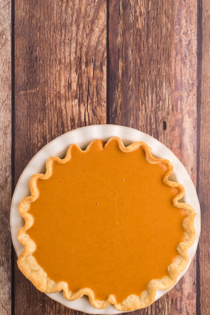 Best Pumpkin Pie Recipe prior to baking on a wood background.