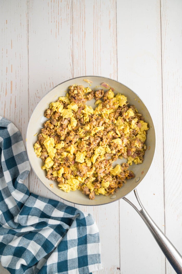 scrambled eggs and sausage in a frying pan.