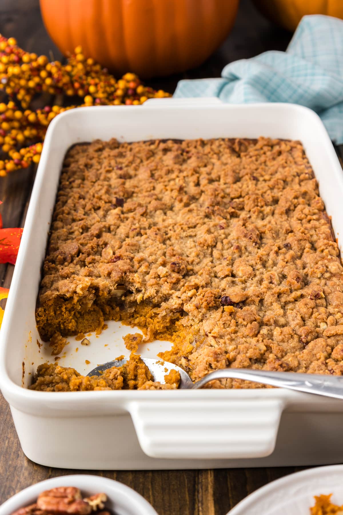 A white casserole dish of pumpkin crisp recipe with a serving scooped out of the lower left corner.