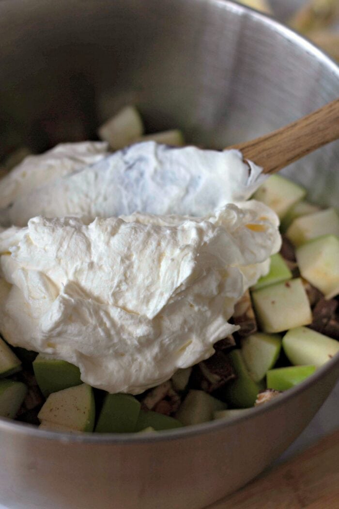 Adding whipped cream and cream cheese to chopped apples and Snickers 