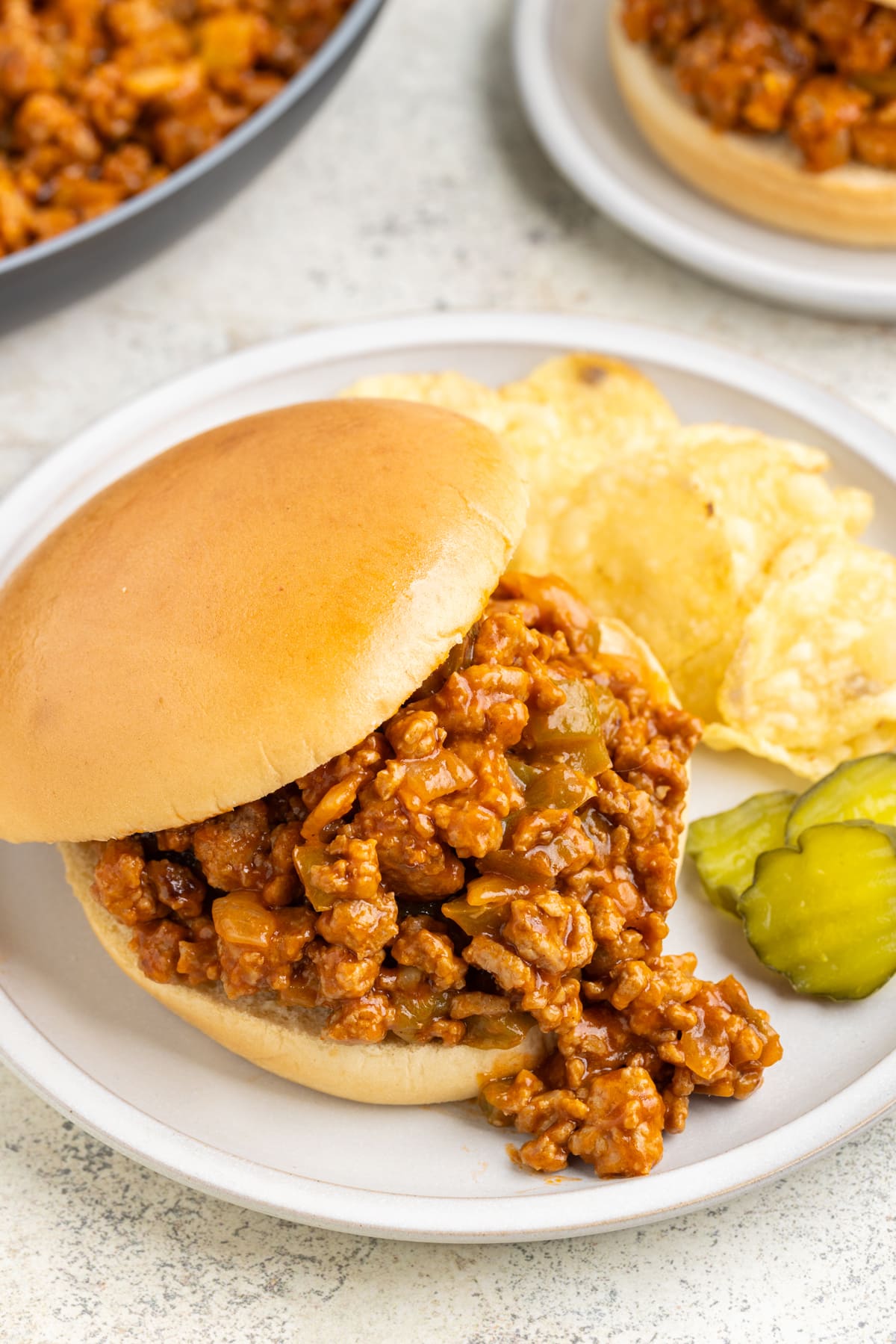 turkey sloppy joes on white plate with chips and pickles