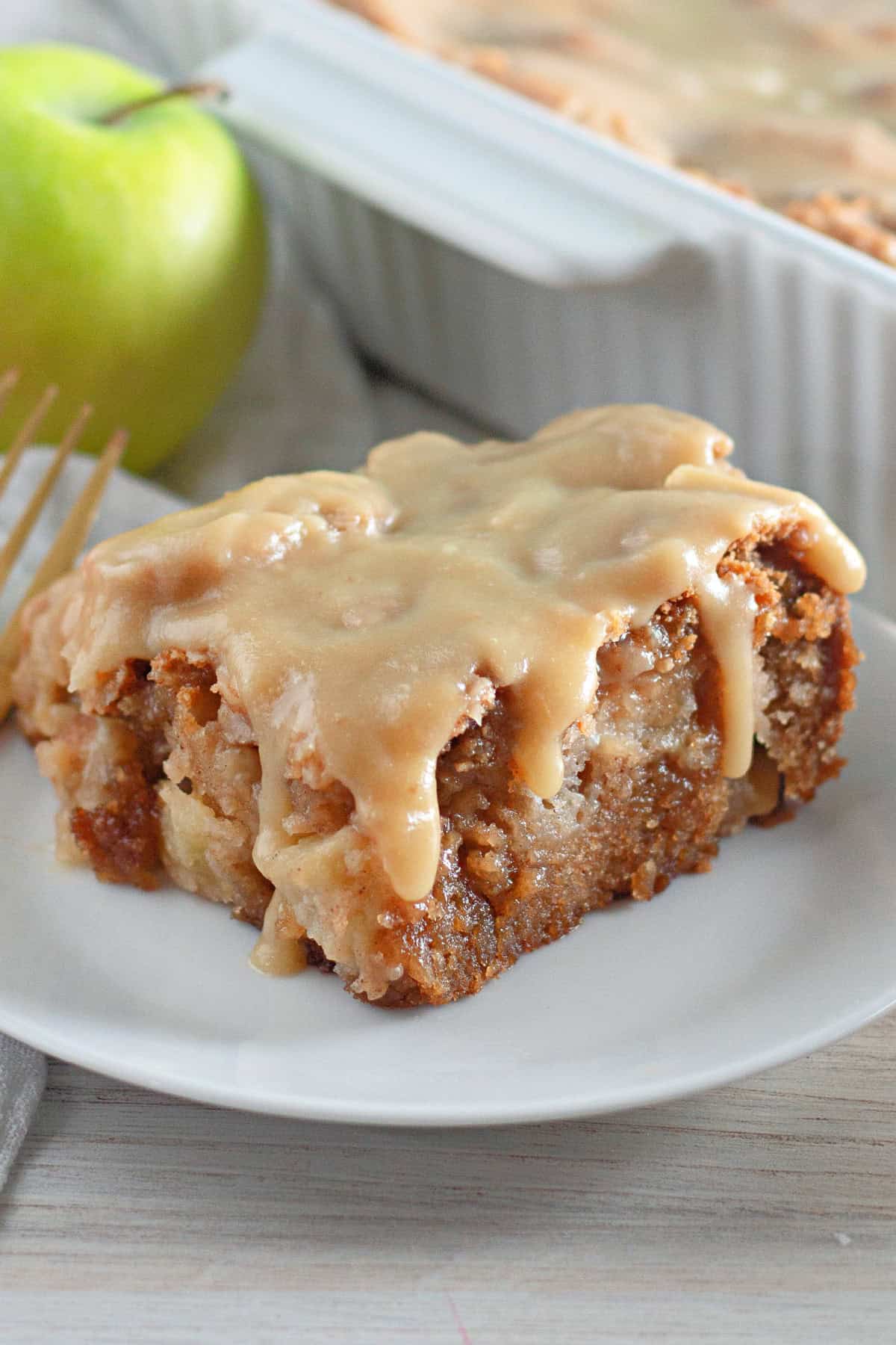 The Apple Dapple Cake is a Fall favorite with fresh diced apples, warm spices and a delicious buttery brown sugar glaze. Apple Dapple Cake on a plate