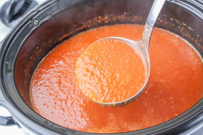 tomato soup being spooned out of a crock pot