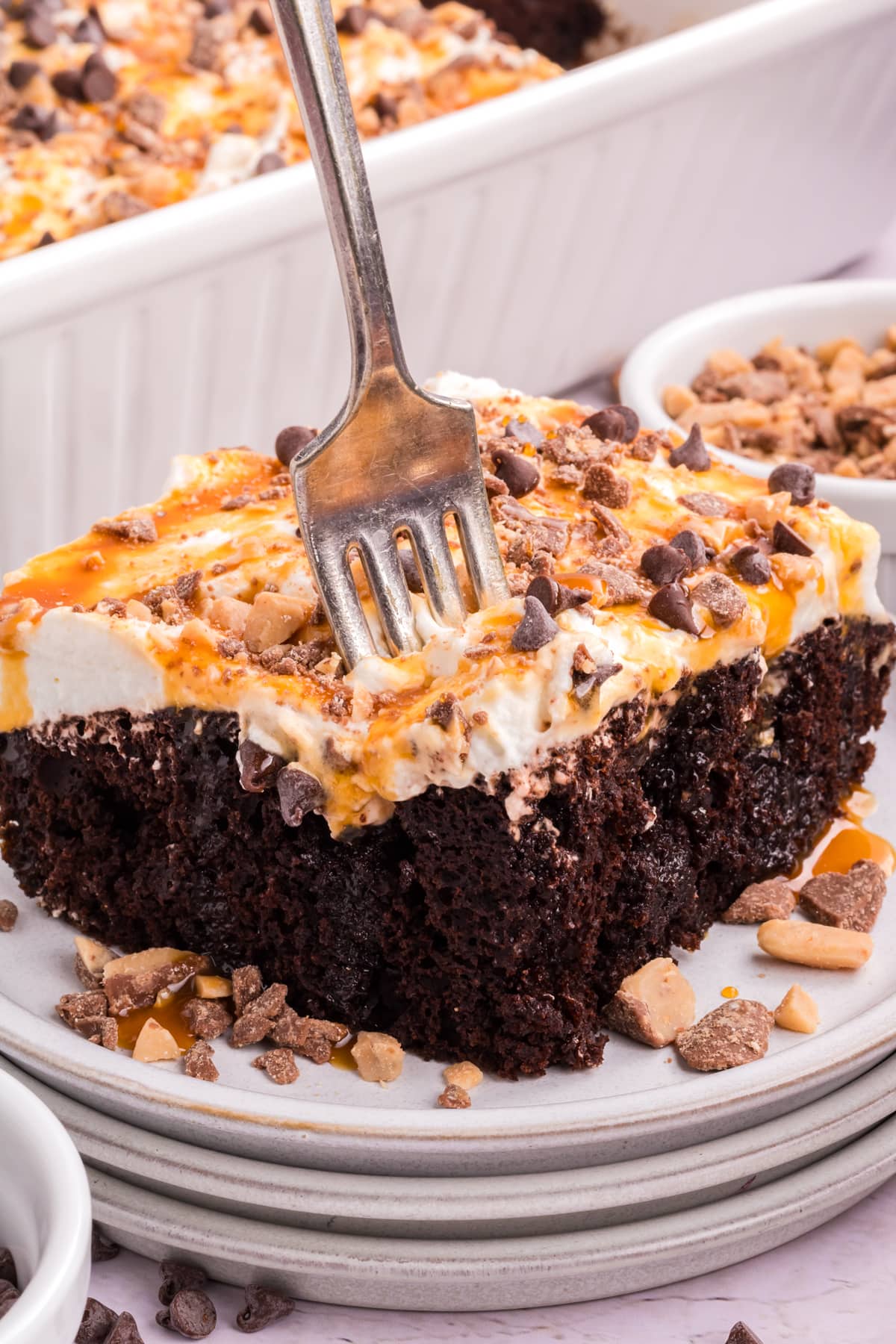 A silver fork in a slice of Chocolate Caramel Poke Cake.