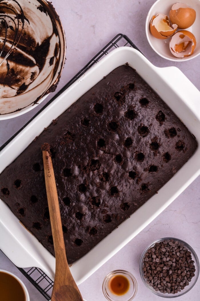 Chocolate cake in a white baking dish with holes for Chocolate Caramel Poke Cake.
