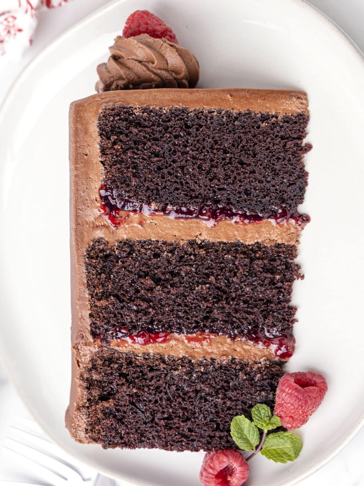 a slice of chocolate raspberry cake with fresh raspberries on a plate