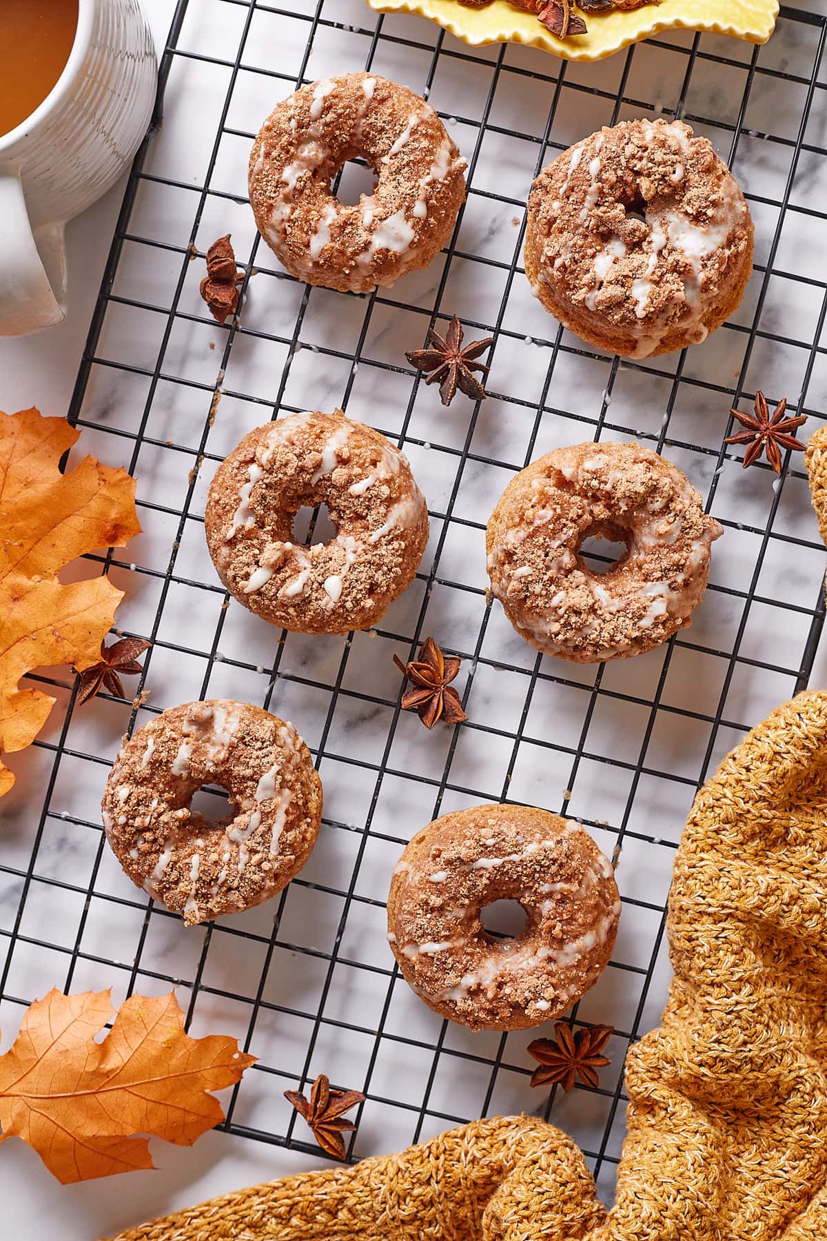 Six crumble topped baked cinnamon donuts on a fall inspired background.