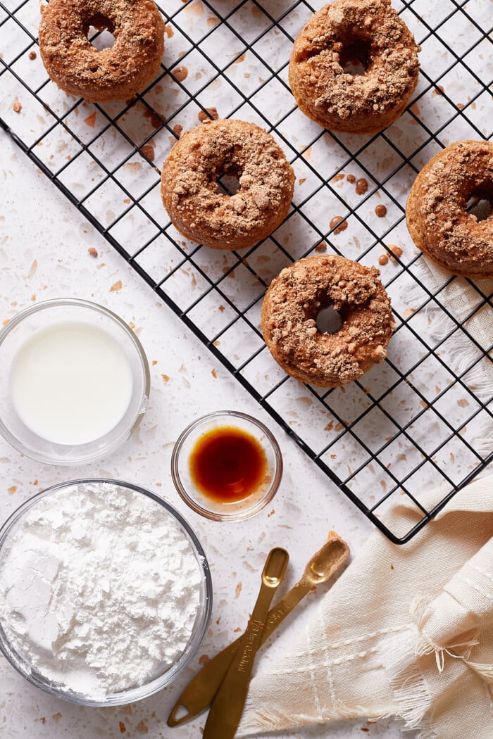 Ingredients for a sugar cream drizzle in bowls alongside cinnamon donuts.