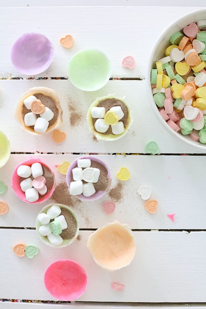 Adding marshmallows and conversation hearts to the chocolate bomb molds
