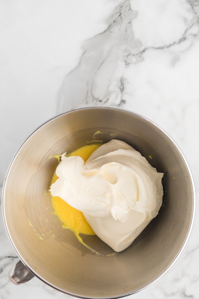 blending together the ingredients for cool whip frosting in a silver mixing bowl.